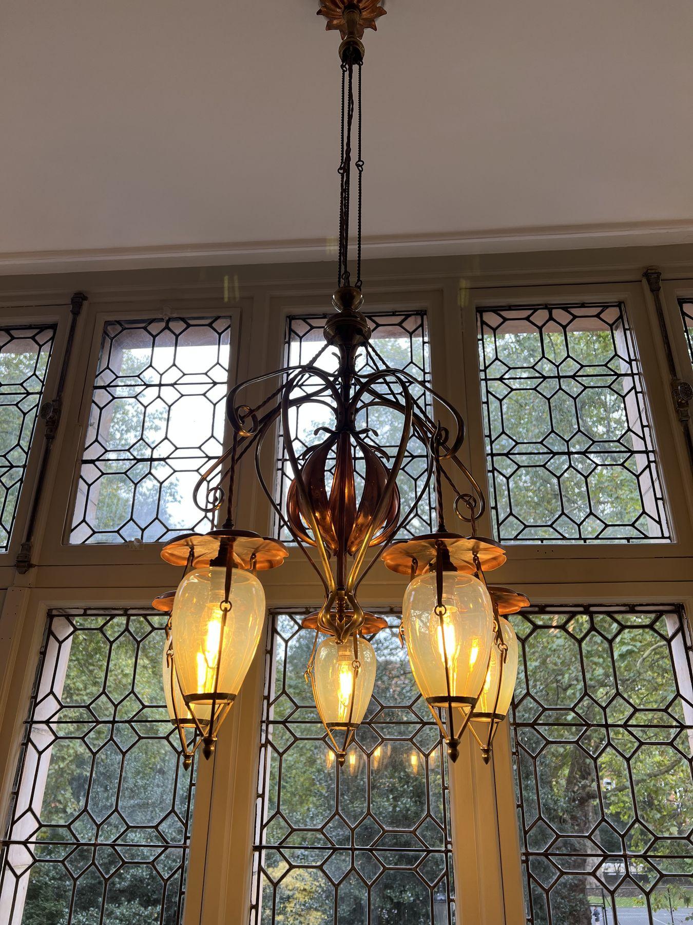Art Nouveau chandelier in front of leaded windows