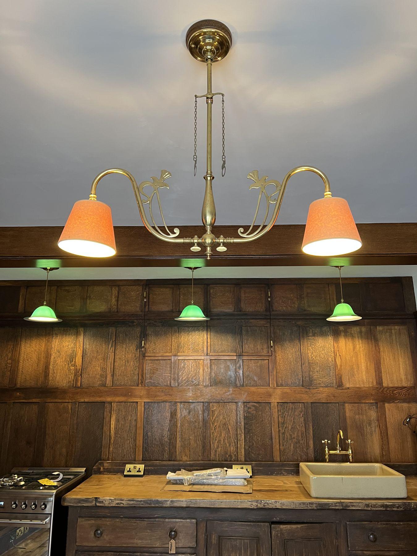 Brass pendant with orange shades over a panelled kitchen